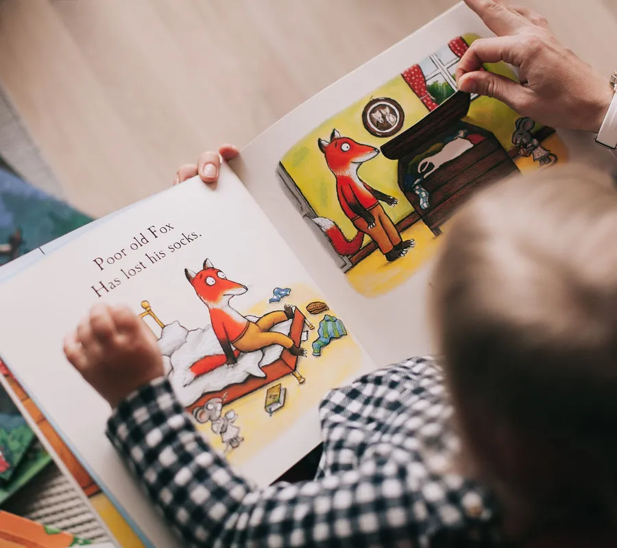 A parent and child reading a picture book together